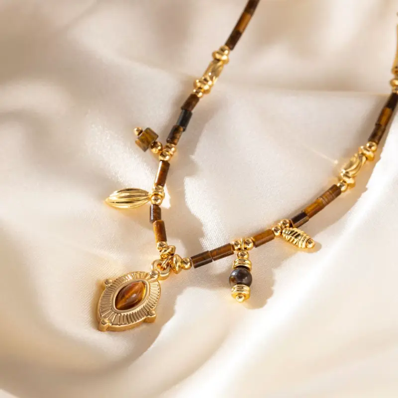 LIVKE’s oval tiger eye necklace with 18K gold-plated chain, styled with black sweater for minimalist elegance.