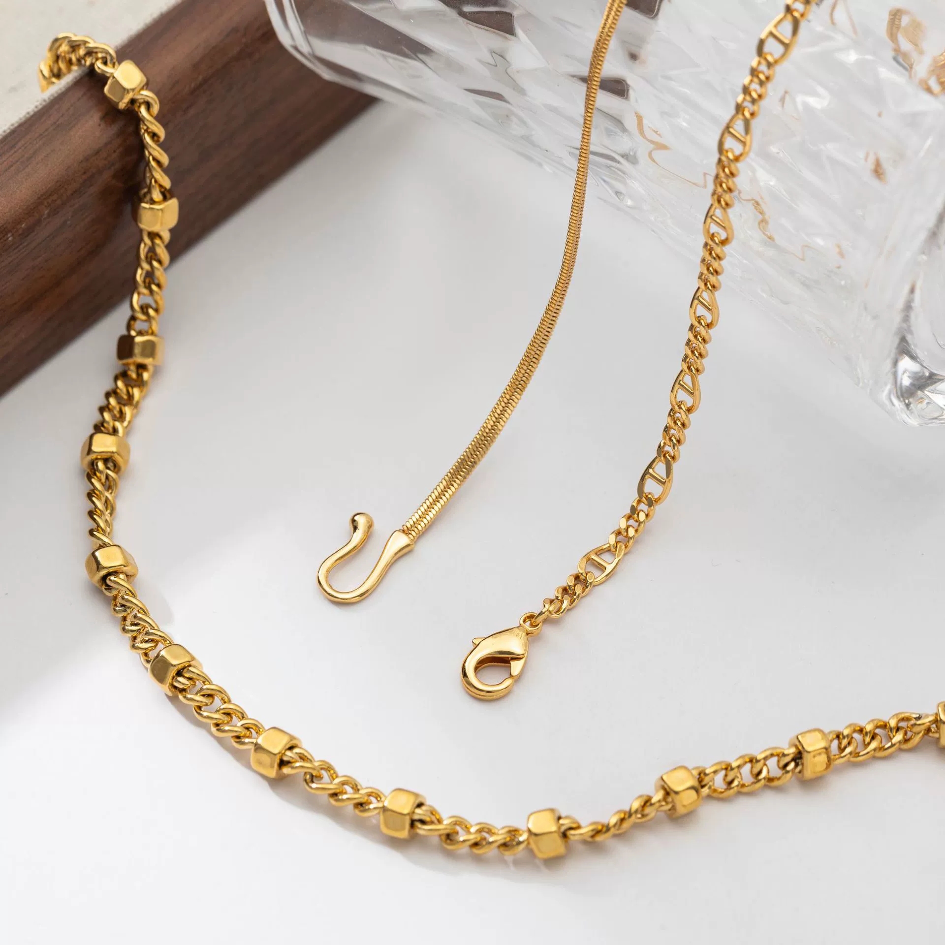 Three LIVKE gold layered necklaces with minimalist pendants, styled over a white tee for casual-chic everyday outfits.