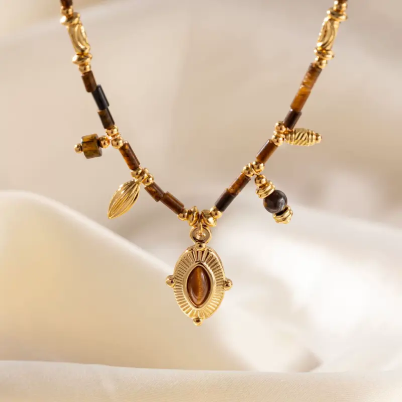 LIVKE’s oval tiger eye necklace with 18K gold-plated chain, styled with black sweater for minimalist elegance.