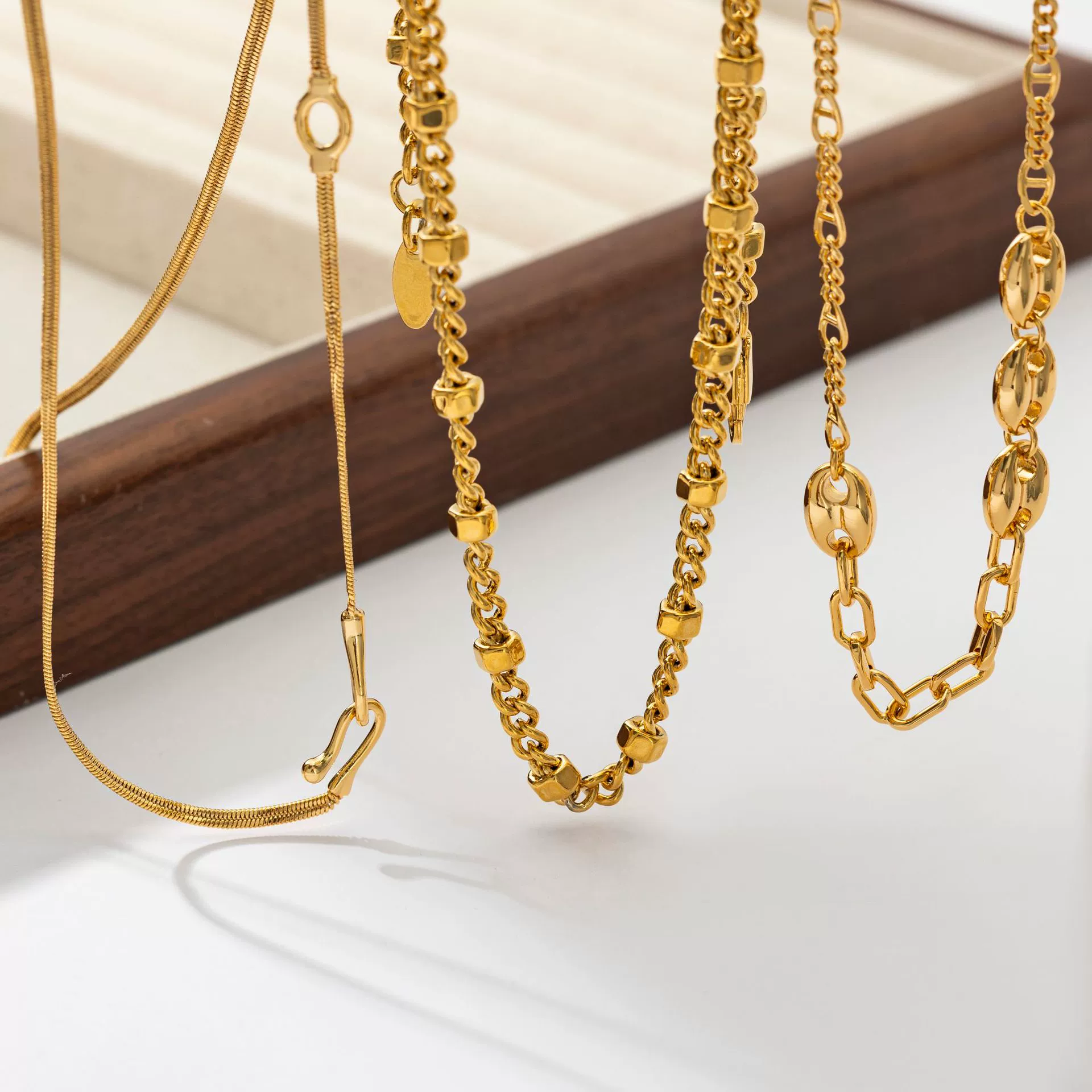Three LIVKE gold layered necklaces with minimalist pendants, styled over a white tee for casual-chic everyday outfits.