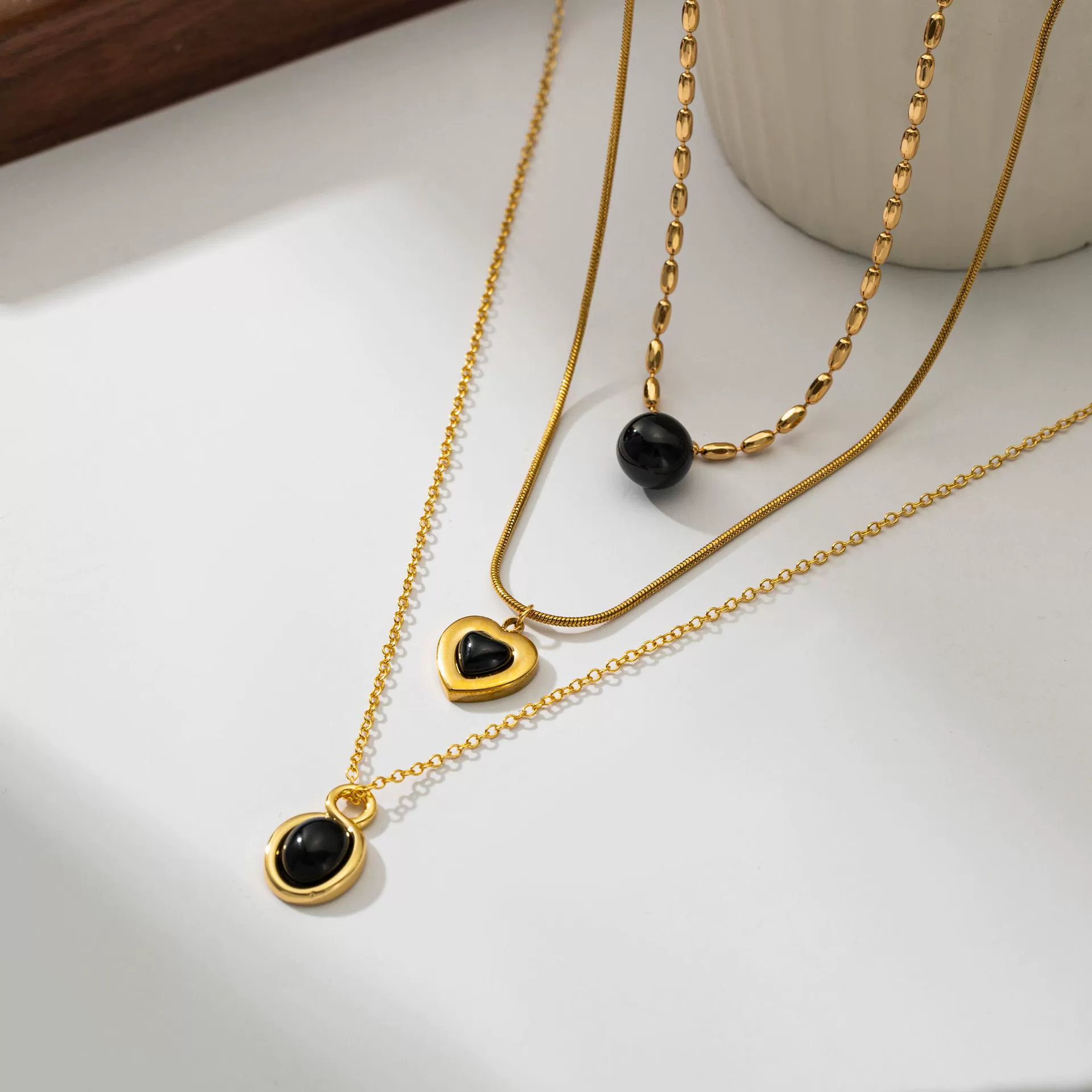 LIVKE’s gold-plated agate heart necklace styled with black silk dress for timeless minimalist elegance