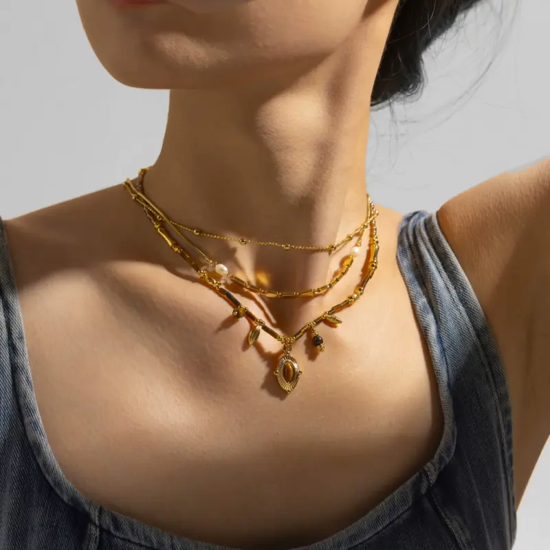 LIVKE’s oval tiger eye necklace with 18K gold-plated chain, styled with black sweater for minimalist elegance.