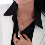 English: “Close-up of LIVKE’s 18K gold plated oval bead necklace in vintage palace style, styled elegantly on a model.”