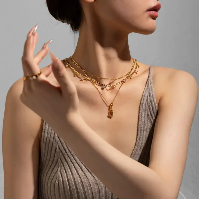 Close-up of LIVKE’s electroplated 18K gold brass zircon stone necklace with a round lock clasp, styled over a chic neckline.