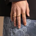 Eclectic woman stacking LIVKE gold textured rings on fingers while browsing vintage market, showcasing bohemian jewelry styling