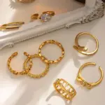 Eclectic woman stacking LIVKE gold textured rings on fingers while browsing vintage market, showcasing bohemian jewelry styling