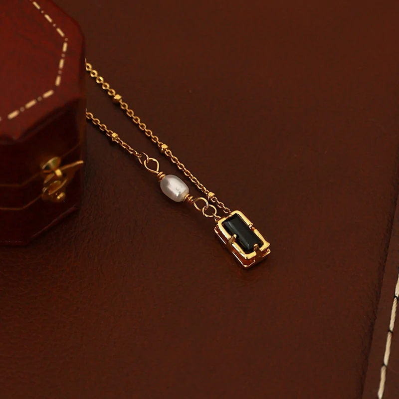 livke-black-cz-pearl-necklace-duo Model wearing LIVKE necklace with black CZ and pearl pendants on collarbone