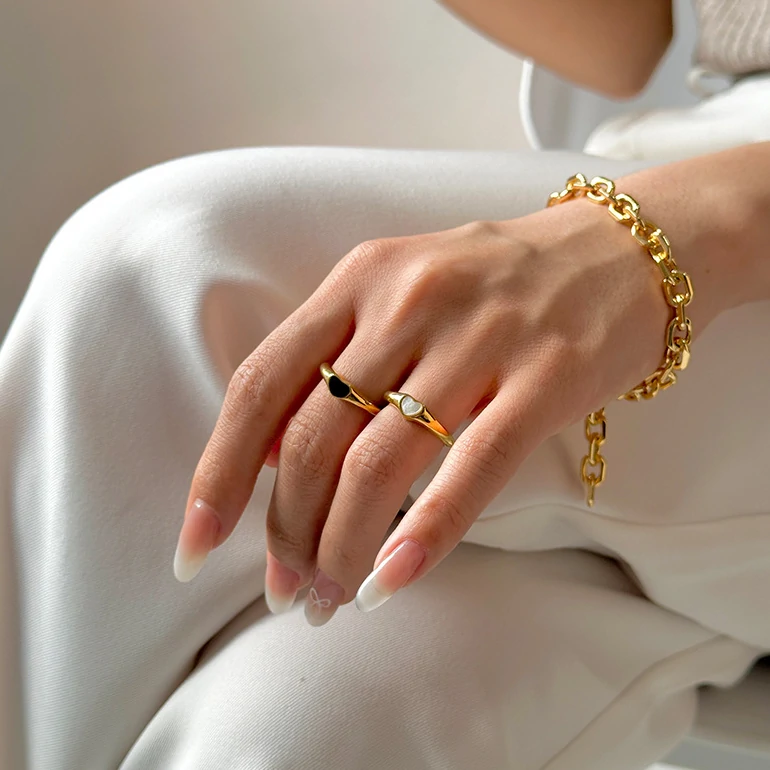Hand wearing LIVKE contrast heart ring with black and white enamel, paired with both tailored suit and casual denim
