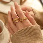 Stacked LIVKE braided and chain rings on hand with bohemian embroidery sleeve, showcasing boho-chic layering.