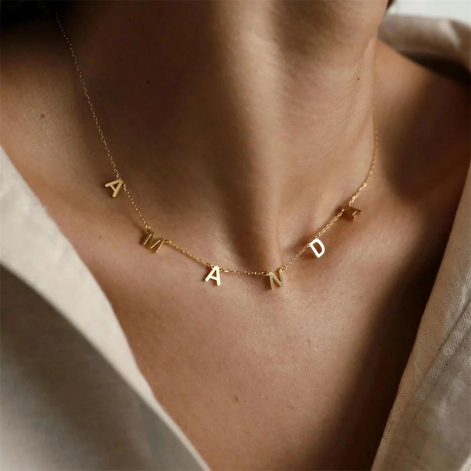 Gold alphabet necklace layered with 4 initials 'LIVK' on collarbone