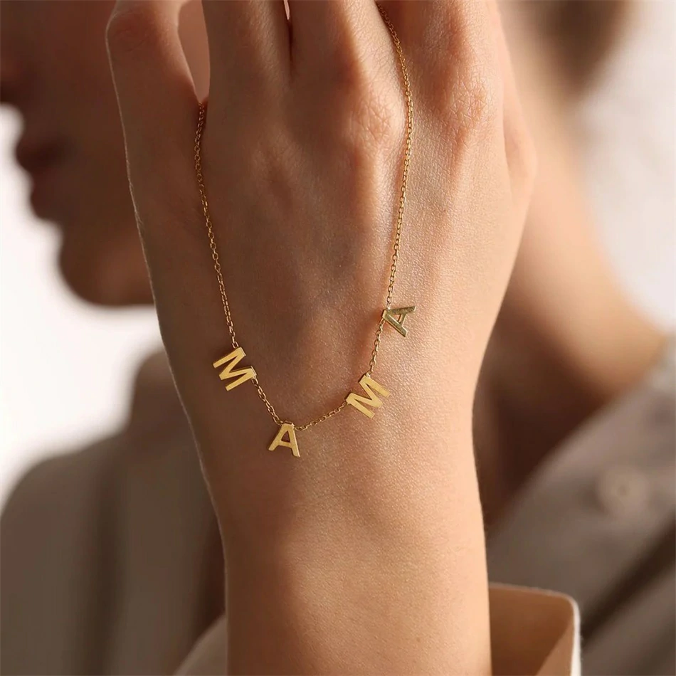 Gold alphabet necklace layered with 4 initials 'LIVK' on collarbone