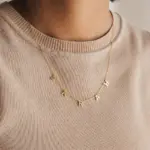 Gold alphabet necklace layered with 4 initials 'LIVK' on collarbone