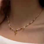 Young woman wearing LIVKE gold cross necklace with layered chains at music festival, blending spiritual jewelry with bohemian style