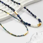 Woman wearing LIVKE lapis lazuli and gold beaded necklace with tailored black dress, showcasing mysterious yet elegant office-to-event jewelry
