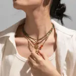 Woman wearing LIVKE cubic zirconia sweater necklace with knitwear and blazer, showcasing versatile minimalist jewelry for work and casual outfits