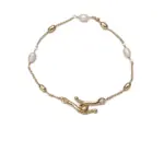 Stylist mixing LIVKE gold chain modules with baroque pearls on antique velvet tray in Paris concept store