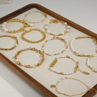 Stylist mixing LIVKE gold chain modules with baroque pearls on antique velvet tray in Paris concept store