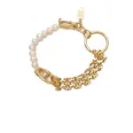 Stylist mixing LIVKE gold chain modules with baroque pearls on antique velvet tray in Paris concept store