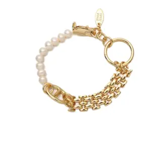 Stylist mixing LIVKE gold chain modules with baroque pearls on antique velvet tray in Paris concept store