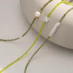 Woman wearing LIVKE pearl and green beaded necklace with silk blouse, showcasing minimalist jewelry for work and evening events