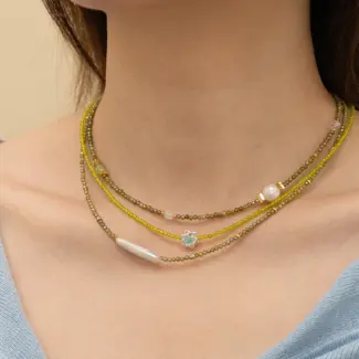 Woman wearing LIVKE pearl and green beaded necklace with silk blouse, showcasing minimalist jewelry for work and evening events