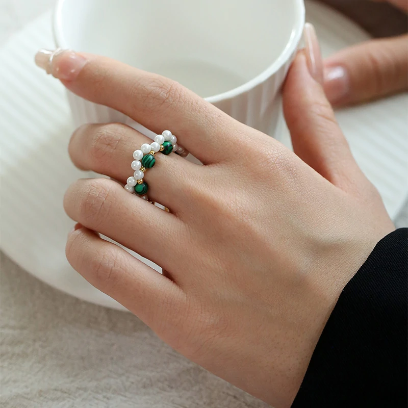 Hand wearing LIVKE adjustable wrap ring with pearls and green aventurine, layered with slim bands for boho chic style