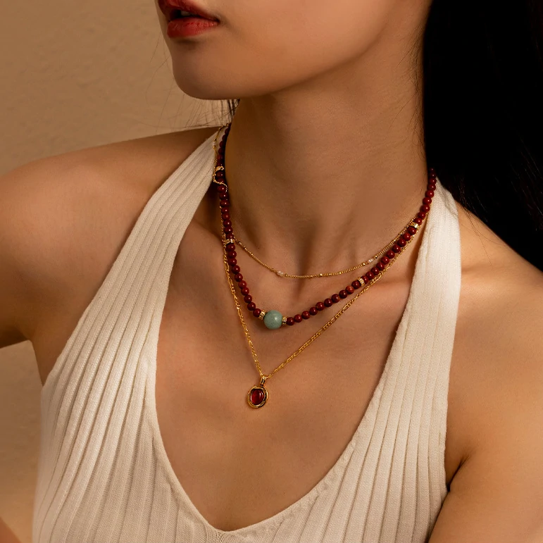 LIVKE’s 18K gold-plated red agate necklace layered with delicate chains on a linen backdrop, styled for boho-chic elegance
