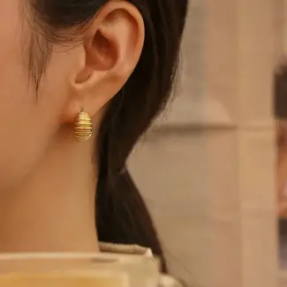 Contemporary art gallery visitor wearing LIVKE gold spiral ear cuffs with minimalist outfit, showcasing architectural jewelry styling