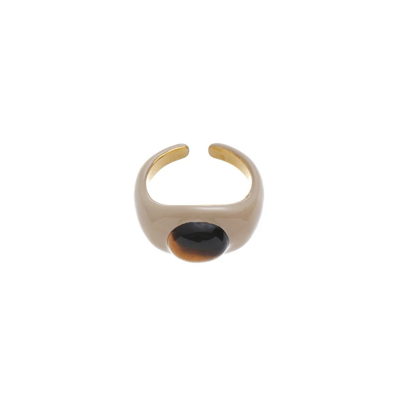 Hand wearing LIVKE adjustable tiger's eye ring layered with slim bands, showcasing bohemian power jewelry on desert-toned fabric