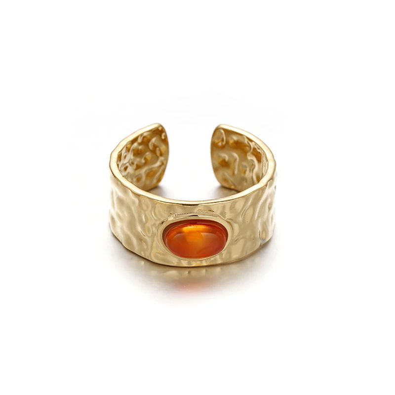 Hand wearing LIVKE red agate titanium ring with textured gold band in boardroom setting, showcasing power jewelry for professionals