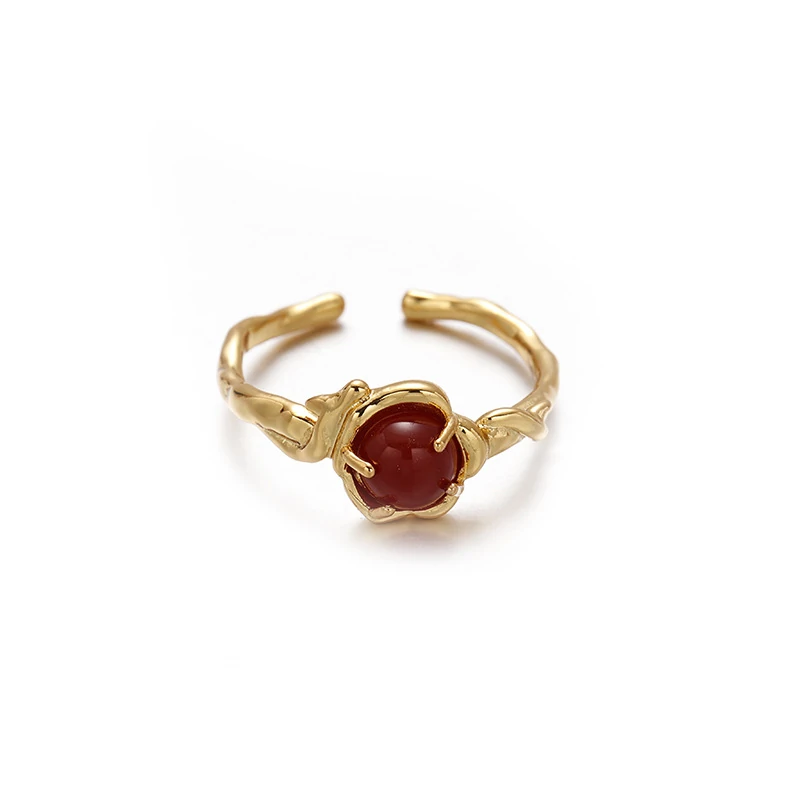 Hand wearing LIVKE red agate titanium ring with textured gold band in boardroom setting, showcasing power jewelry for professionals
