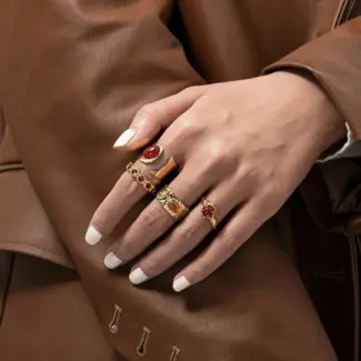 Hand wearing LIVKE red agate titanium ring with textured gold band in boardroom setting, showcasing power jewelry for professionals