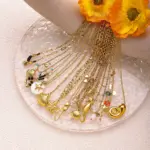 Natural tumbled shell pendant on 18K gold-plated chain styled with linen shirt and jeans at beachside café