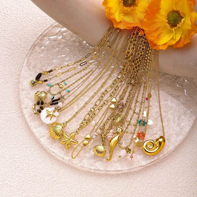 Natural tumbled shell pendant on 18K gold-plated chain styled with linen shirt and jeans at beachside café