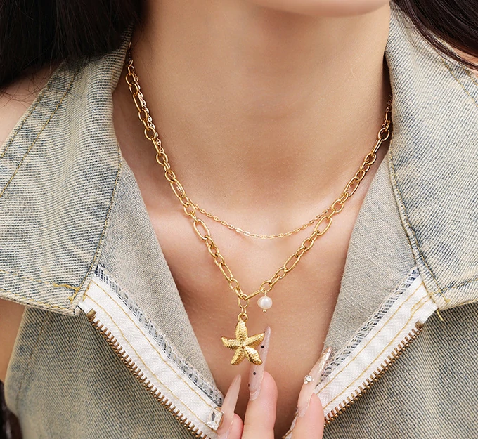 Natural tumbled shell pendant on 18K gold-plated chain styled with linen shirt and jeans at beachside café