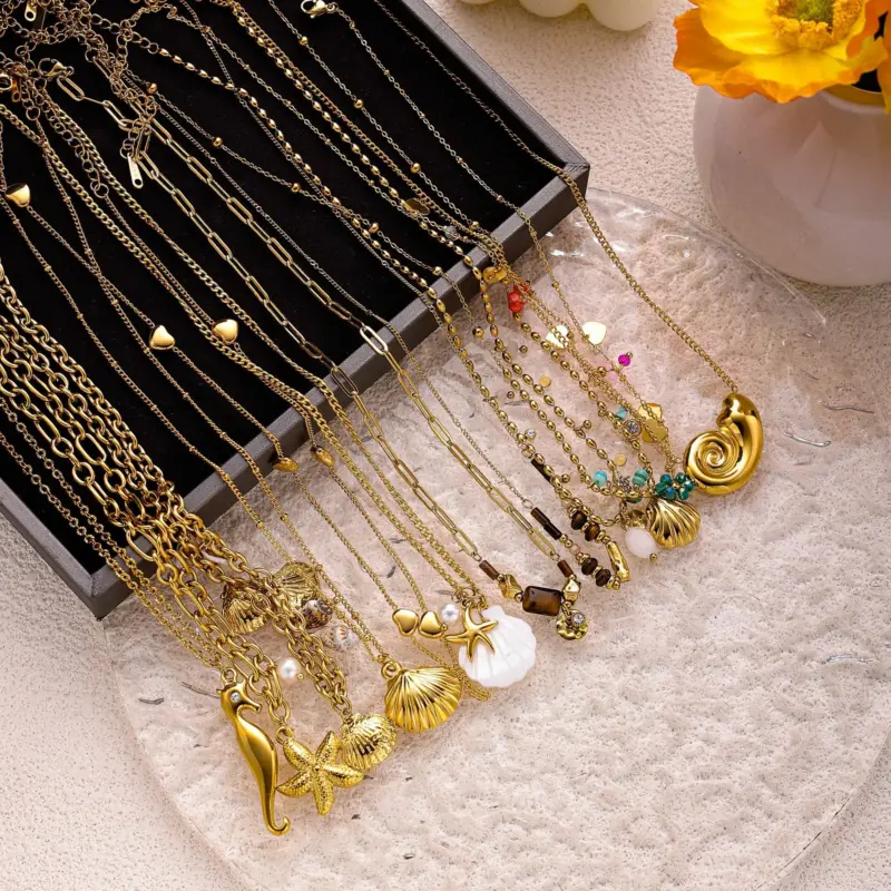 Natural tumbled shell pendant on 18K gold-plated chain styled with linen shirt and jeans at beachside café