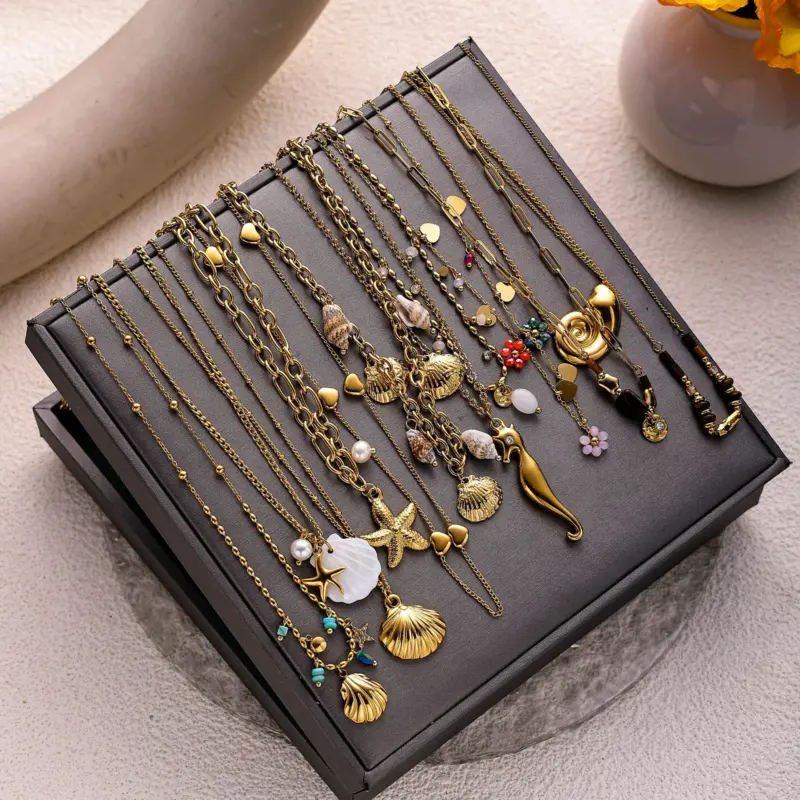 Natural tumbled shell pendant on 18K gold-plated chain styled with linen shirt and jeans at beachside café