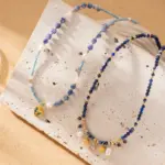 LIVKE 18K gold-plated layered necklace with colored pearls and zirconia, styled with linen and seashells for coastal minimalist aesthetic