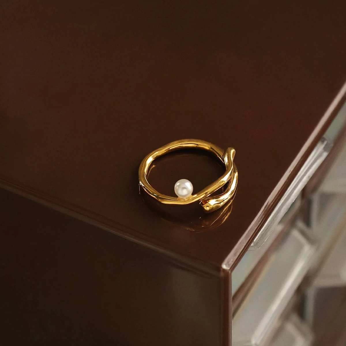 livke-wave-band-pearl-ring-adjusting Hand model adjusting open wave ring with pearl under golden hour sunlight