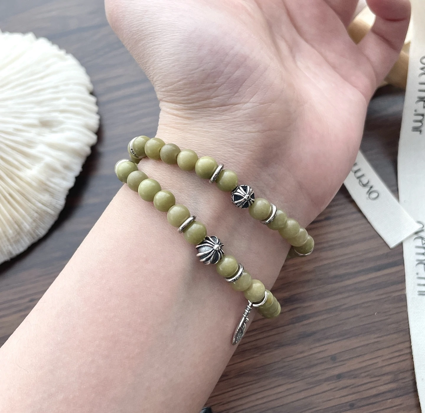 livke-sacred-forest-bracelet-energy-healing (2) Olive green aventurine bead bracelet with silver feather charm and floral spacer beads, designed for spiritual healing and crystal energy jewelry lovers